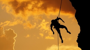 Silhouette of a climber on a vertical wall over beautiful sunset