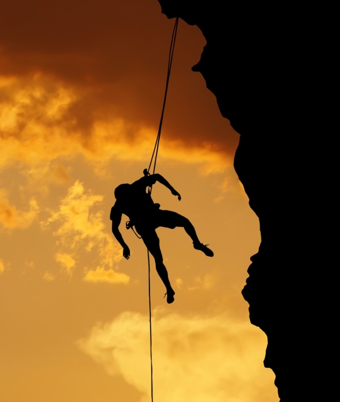 Silhouette of a climber on a vertical wall over beautiful sunset